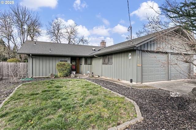 rear view of property featuring a garage, fence, driveway, a lawn, and a chimney