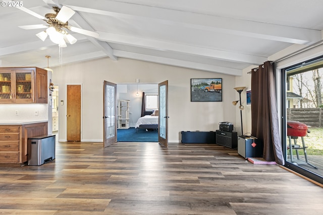 interior space featuring vaulted ceiling with beams, a ceiling fan, baseboards, and wood finished floors