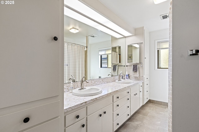 full bath featuring double vanity, visible vents, and a sink