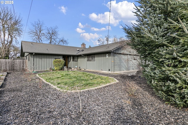 back of property featuring an attached garage, a chimney, and fence