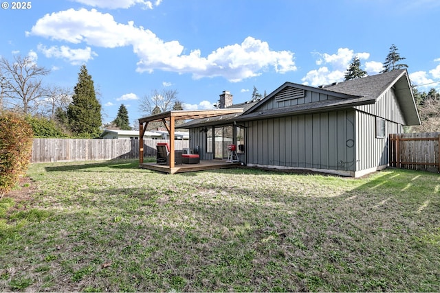 back of property featuring a deck, board and batten siding, a fenced backyard, and a lawn