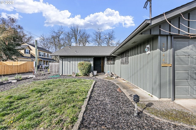 exterior space with board and batten siding, a yard, fence, and an attached garage