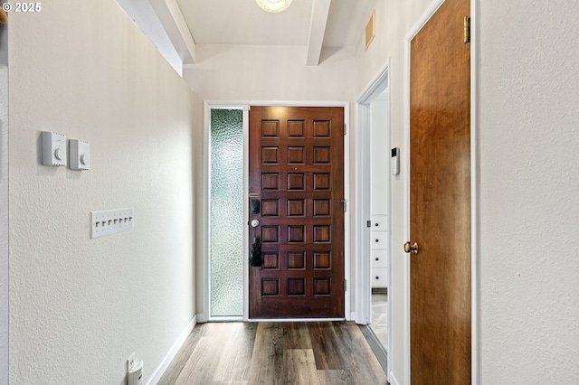 entrance foyer featuring a textured wall, wood finished floors, visible vents, and baseboards