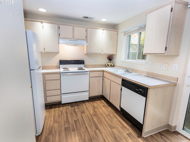 kitchen with white appliances, visible vents, under cabinet range hood, wood finished floors, and a sink