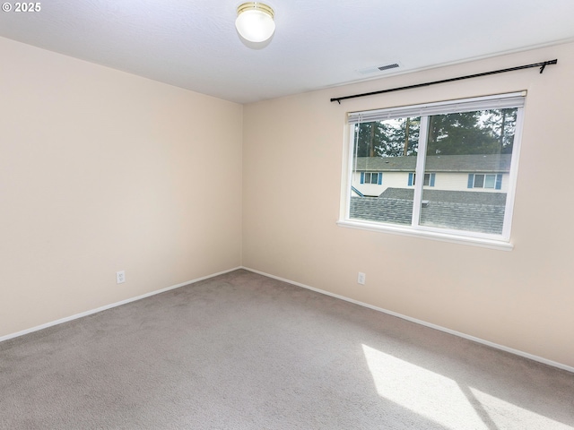 unfurnished room featuring carpet flooring, visible vents, and baseboards
