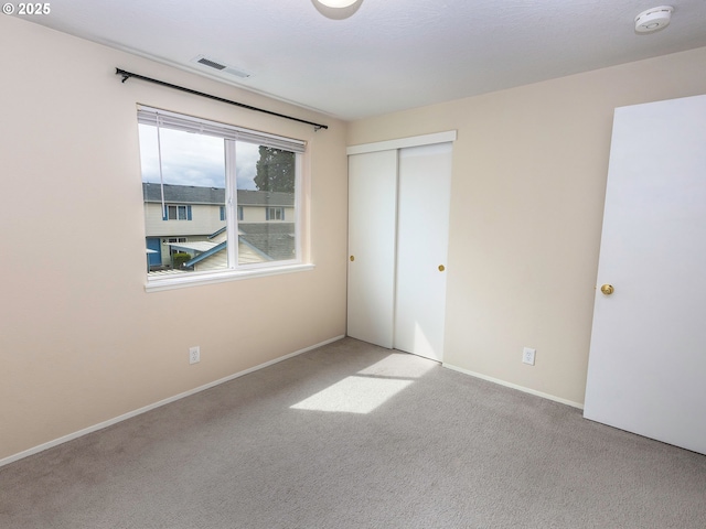 unfurnished bedroom with a closet, carpet flooring, baseboards, and visible vents