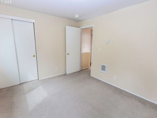 unfurnished bedroom featuring carpet, visible vents, a closet, and baseboards