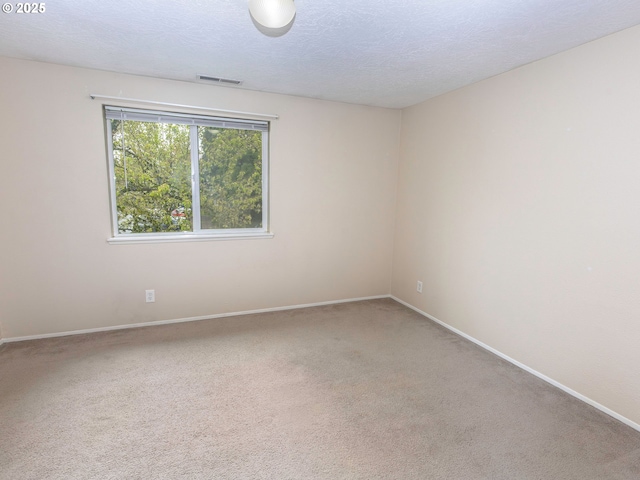 empty room featuring visible vents, baseboards, light colored carpet, and a textured ceiling