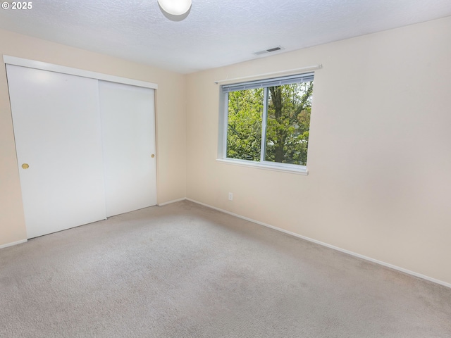 unfurnished bedroom with a closet, carpet flooring, visible vents, and a textured ceiling