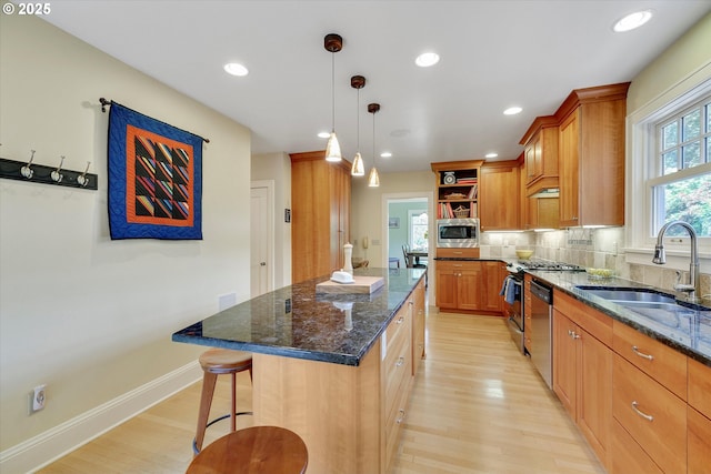 3034 NE Tillamook St, Portland, OR 97212 - kitchen featuring appliances with stainless steel finishes, open shelves, light wood finished floors, a center island, and dark stone countertops