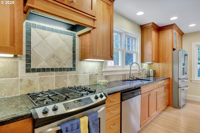 3034 NE Tillamook St, Portland, OR 97212 - kitchen featuring appliances with stainless steel finishes, dark stone countertops, light wood-type flooring, custom range hood, and backsplash