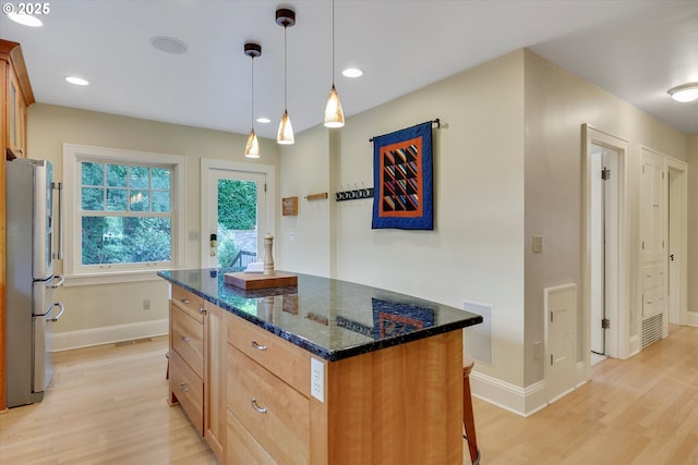 3034 NE Tillamook St, Portland, OR 97212 - kitchen featuring freestanding refrigerator, light wood-style floors, a center island, dark stone counters, and pendant lighting