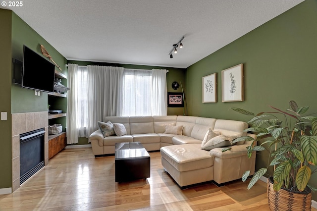 living room with a textured ceiling, light wood-type flooring, and a fireplace