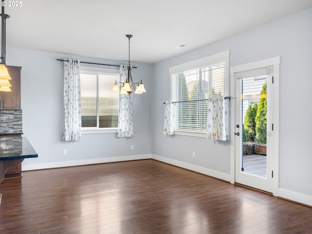 unfurnished dining area with dark hardwood / wood-style floors and a notable chandelier