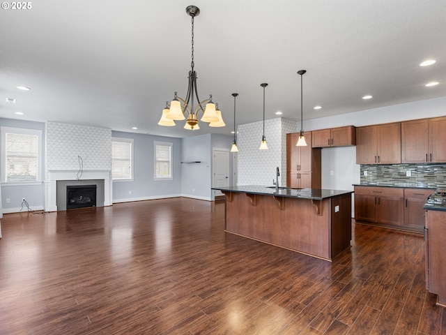 kitchen featuring hanging light fixtures, a kitchen breakfast bar, a wealth of natural light, a fireplace, and a kitchen island with sink