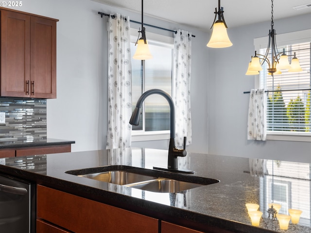 kitchen with hanging light fixtures, sink, dark stone counters, and decorative backsplash