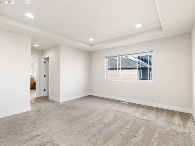 carpeted empty room with a raised ceiling