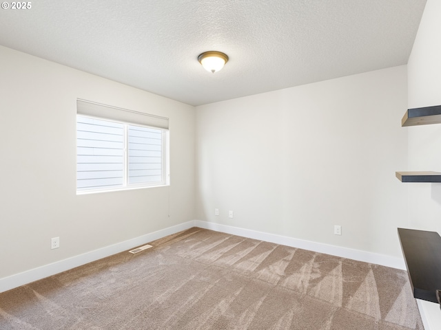 carpeted empty room featuring a textured ceiling