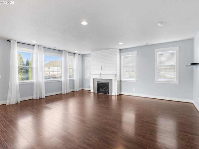 unfurnished living room featuring dark wood-type flooring, a fireplace, and a textured ceiling