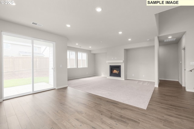 8836 SW Peia Ln, Tualatin, OR 97062 - unfurnished living room featuring baseboards, a glass covered fireplace, wood finished floors, and recessed lighting