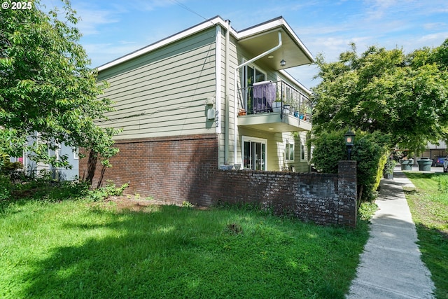 view of side of home with a balcony and a yard