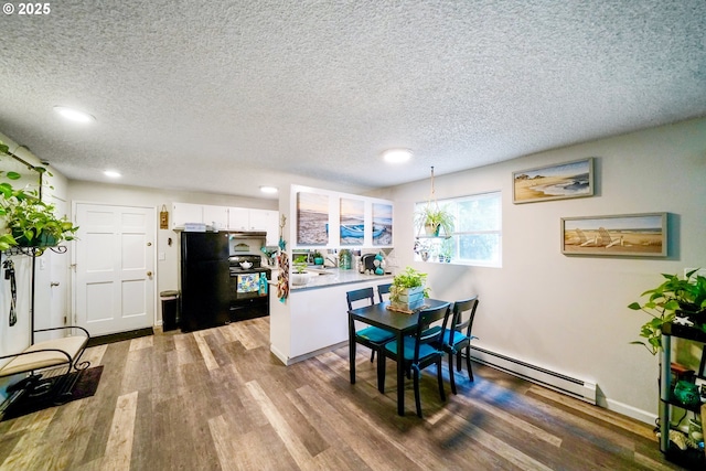 dining space featuring a baseboard radiator, hardwood / wood-style floors, and a textured ceiling