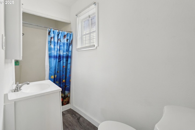 bathroom featuring baseboards, a shower with shower curtain, toilet, vanity, and wood finished floors