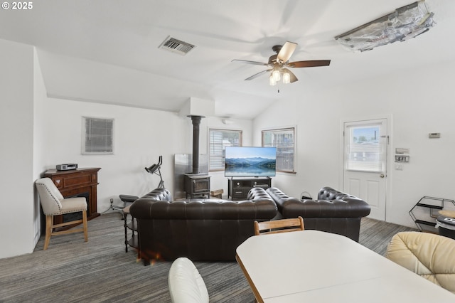 living room with visible vents, a wood stove, a ceiling fan, and plenty of natural light