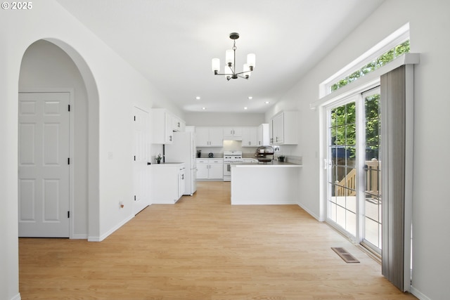 kitchen with white appliances, a chandelier, light wood-style floors, light countertops, and white cabinetry