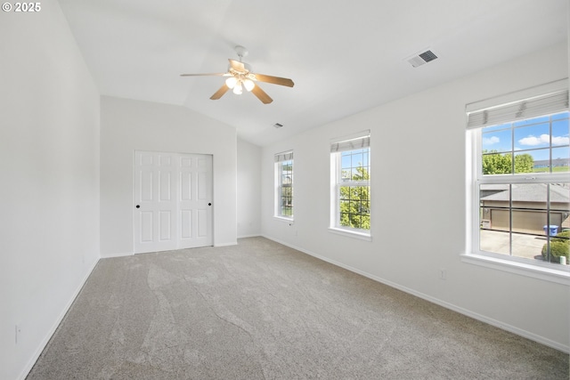 unfurnished bedroom featuring multiple windows, vaulted ceiling, carpet, and baseboards