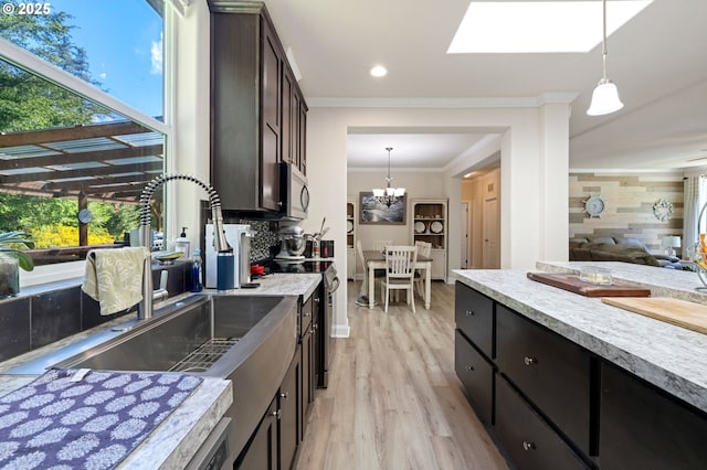 87477 Jean Dr, Bandon, OR 97411 - kitchen featuring a sink, ornamental molding, light wood-style flooring, stainless steel microwave, and pendant lighting