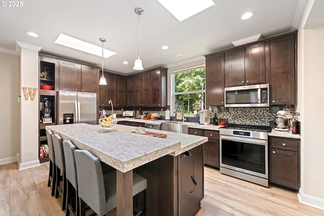 87477 Jean Dr, Bandon, OR 97411 - kitchen featuring appliances with stainless steel finishes, dark brown cabinetry, a skylight, light countertops, and tasteful backsplash