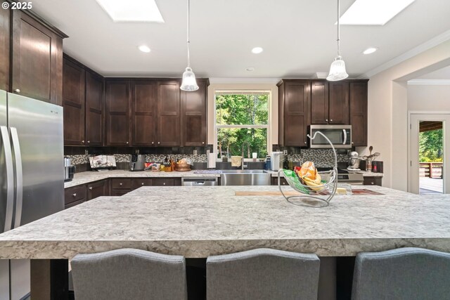 87477 Jean Dr, Bandon, OR 97411 - kitchen with appliances with stainless steel finishes, dark brown cabinetry, crown molding, light countertops, and tasteful backsplash