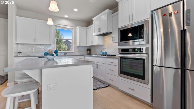 11649 SE Pleasant Valley Pkwy, Happy Valley, OR 97086 - kitchen featuring appliances with stainless steel finishes, a kitchen breakfast bar, white cabinetry, recessed lighting, and backsplash