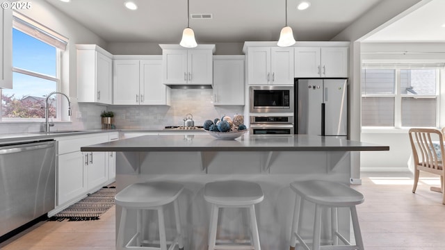 11649 SE Pleasant Valley Pkwy, Happy Valley, OR 97086 - kitchen featuring appliances with stainless steel finishes, recessed lighting, white cabinetry, tasteful backsplash, and a kitchen breakfast bar