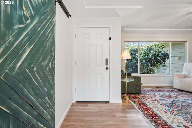 entryway with a barn door, baseboards, and wood finished floors