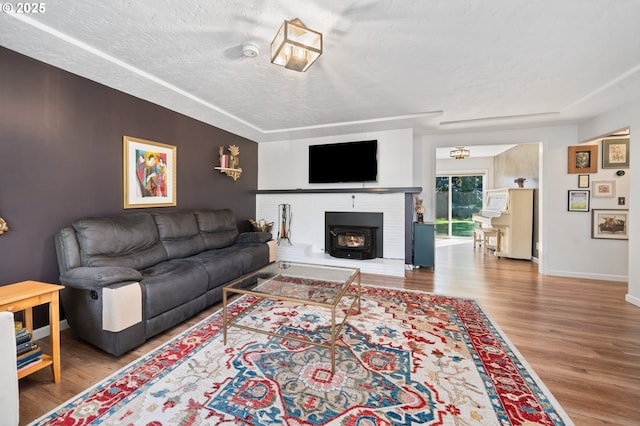 living room with a textured ceiling, baseboards, and wood finished floors