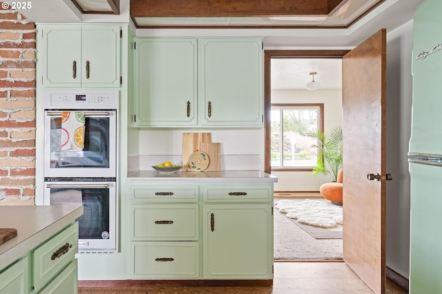 kitchen with green cabinets, double oven, and light countertops