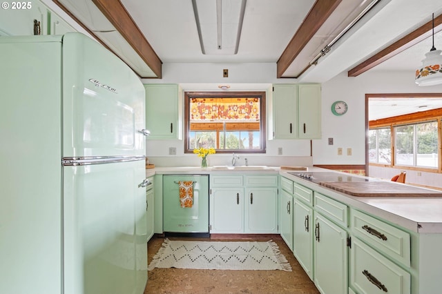 kitchen with green cabinetry, dishwashing machine, a sink, and freestanding refrigerator