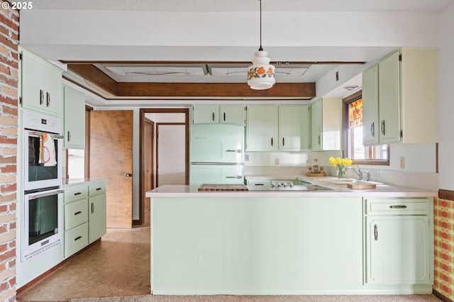 kitchen featuring a sink, white appliances, a peninsula, green cabinets, and light countertops