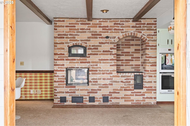 details featuring carpet, beamed ceiling, a wainscoted wall, double wall oven, and a textured ceiling