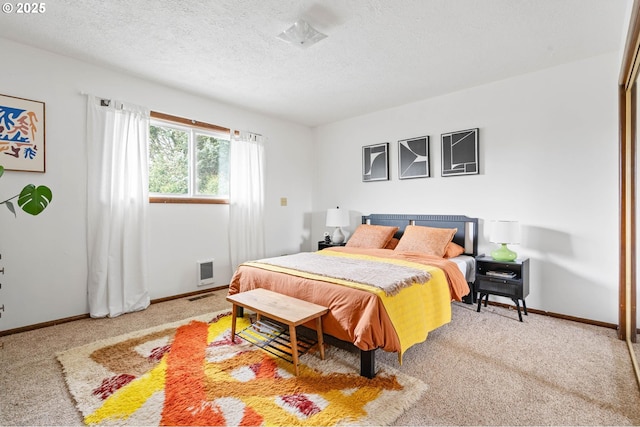 bedroom with carpet flooring, visible vents, baseboards, and a textured ceiling