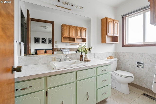 bathroom with tile patterned flooring, tile walls, toilet, wainscoting, and vanity