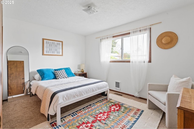 bedroom featuring baseboards, carpet floors, a textured ceiling, and visible vents