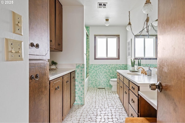 full bath featuring vanity, visible vents, a wainscoted wall, tile walls, and toilet