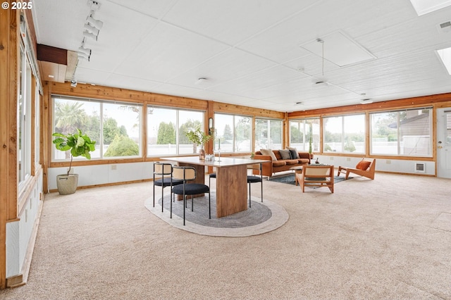 sunroom featuring rail lighting, a healthy amount of sunlight, and visible vents