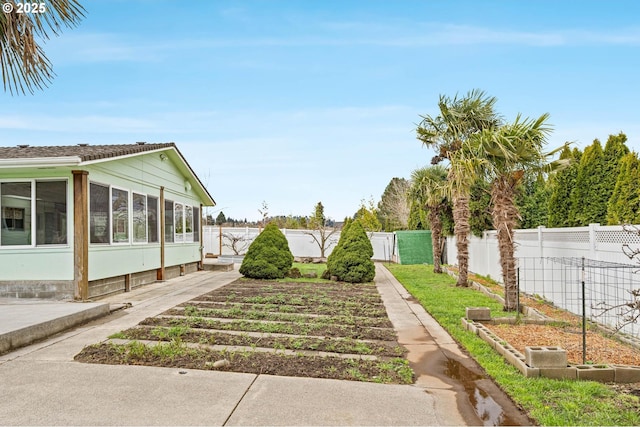 view of yard with a gate, a fenced backyard, and a sunroom