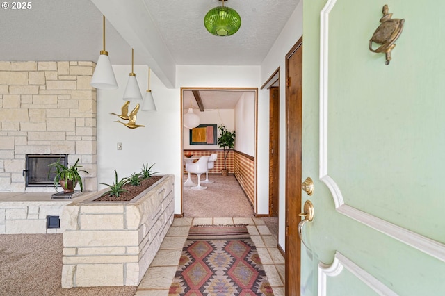 interior space with a textured ceiling, a wainscoted wall, and light carpet