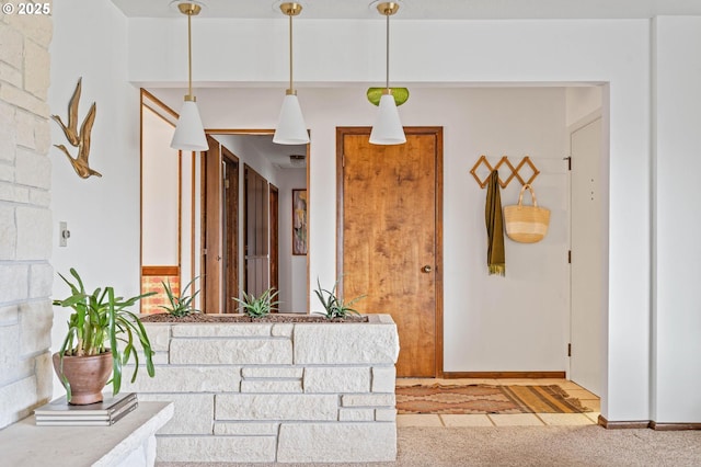 interior space with light countertops, decorative light fixtures, baseboards, and light carpet