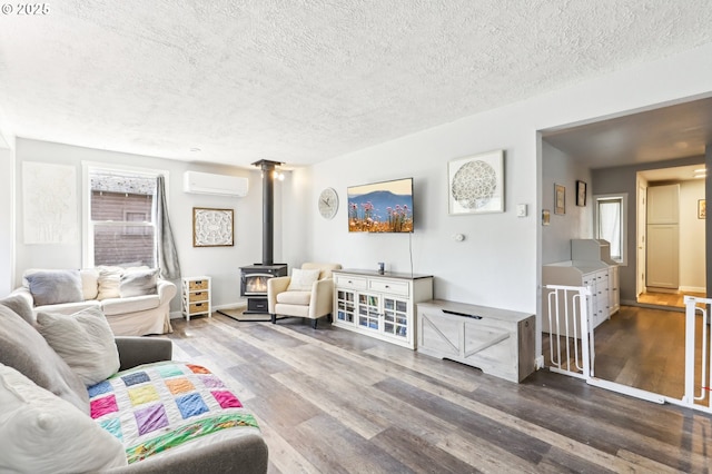 living room with wood finished floors, a wood stove, a textured ceiling, and a wall mounted AC